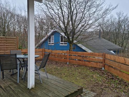 a table and chairs on a deck with a blue house at Ferienhaus Fuchsbau in Extertal