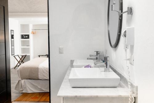 a white bathroom with a sink and a bed at Hotel La Morada in San Miguel de Allende