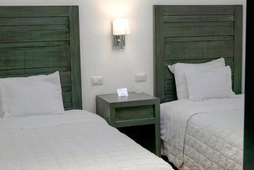 a hotel room with two beds and a night stand at Hotel La Morada in San Miguel de Allende