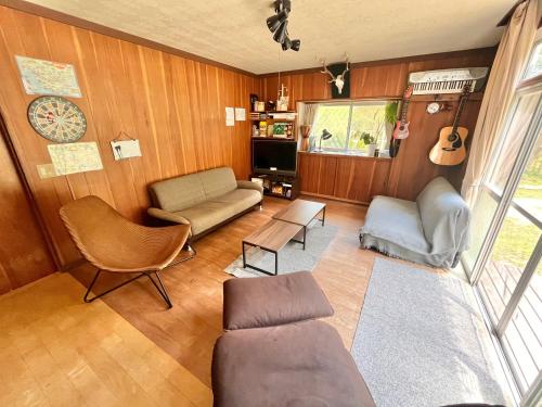 a living room with a couch and chairs and a guitar at Cruise garden in Kanō
