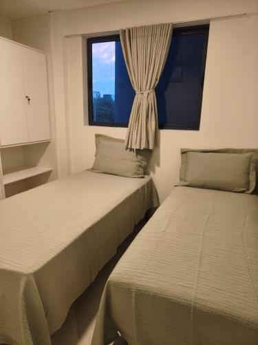 two beds in a room with a window at PARK DEL PRADO - Conforto pertinho do mar in Cabedelo