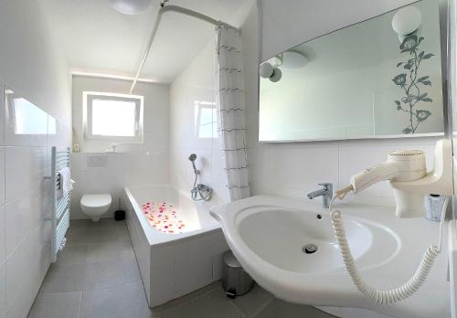 a bathroom with a sink and a tub and a toilet at Hotel Ascona Bad Krozingen Frisch renoviert in bester Lage, nahe Autobahn, Kurpark und Vita Classica in Bad Krozingen