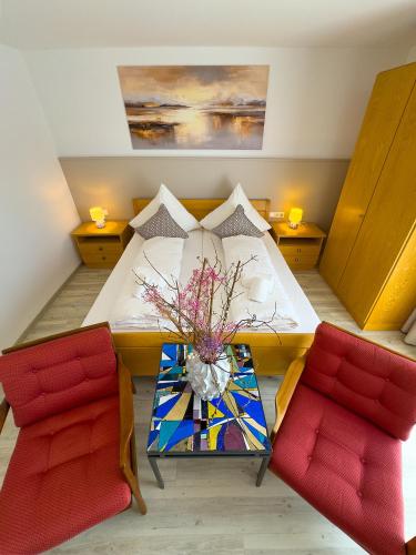 a room with a table and two red chairs at Hotel Ascona Bad Krozingen Frisch renoviert in bester Lage, nahe Autobahn, Kurpark und Vita Classica in Bad Krozingen