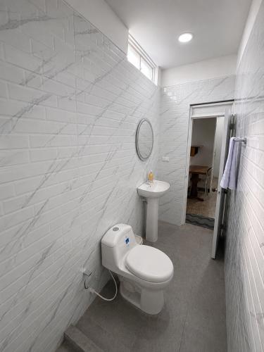 a white bathroom with a toilet and a sink at Hotel Luna Del Rio in Puerto Salgar