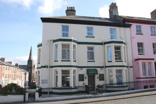 a white house with a steeple on a street at Kimberley House in Whitby