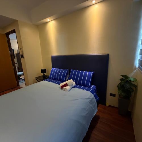 a bedroom with a large bed with blue pillows at R2 condotel 2BR Santorini tower in Cainta