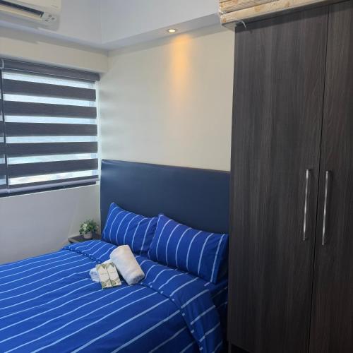 a bedroom with a blue bed and a wooden cabinet at R2 condotel 2BR Santorini tower in Cainta