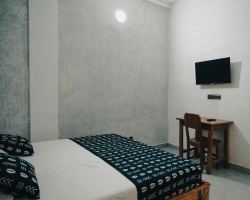a bedroom with a bed and a desk and a television at Hôtel Merveille Lomé in Lomé