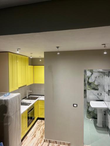 an empty kitchen with yellow cabinets and a sink at City Centre Rooms 4R in Shkodër