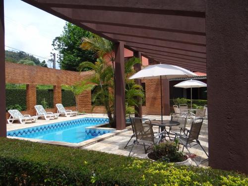 un patio con mesa, sillas y piscina en Pousada da Mantiqueira, en Visconde De Maua
