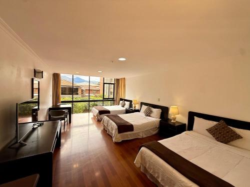 a hotel room with two beds and a large window at Hotel NASS Pinar del Lago in Cuenca