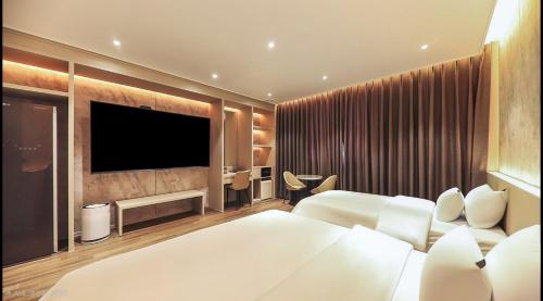 a bedroom with two beds and a flat screen tv at Hotel RIL in Gwangju