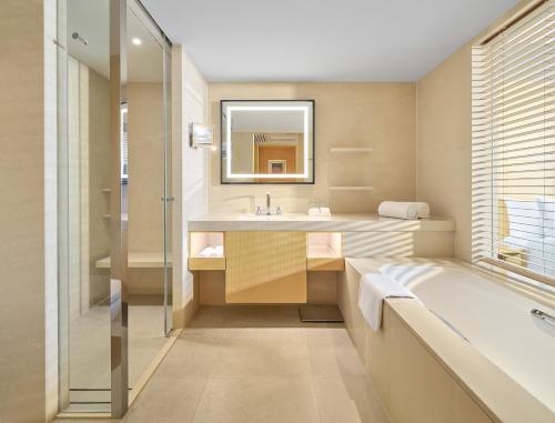 a bathroom with a tub and a sink and a mirror at Marco Polo Wuhan in Wuhan