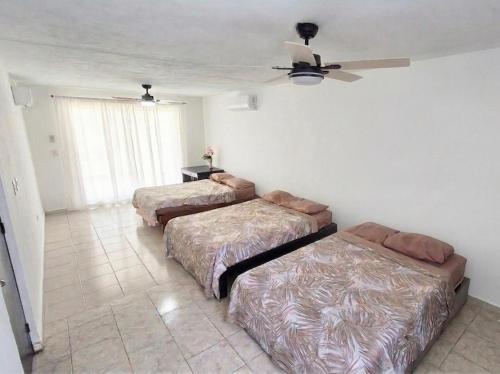 a bedroom with two beds and a ceiling fan at Casa Amplia San Pedro Norte Cerca Fco Montejo in Mérida