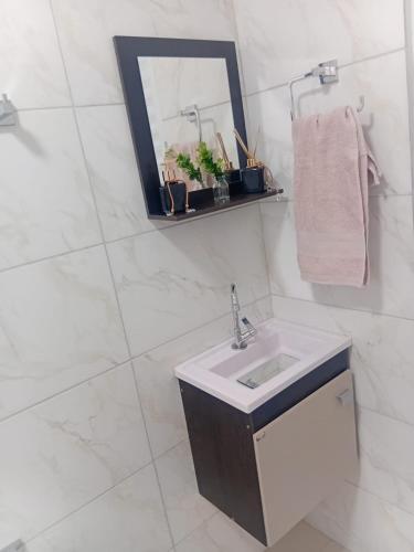 a white bathroom with a sink and a mirror at Pousada Do Goiano in Manhã