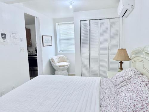 a white bedroom with a white bed and a chair at 2265 Bruckner Blvd Apartments in Bronx
