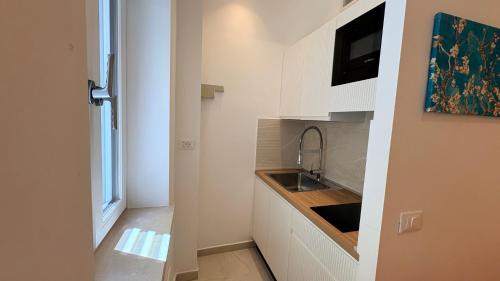 a kitchen with white cabinets and a sink and a television at Althea B&B in Schiavonea
