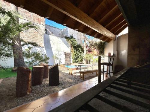 a patio with a table and chairs and a table and a tree at Pulkay Hostel Folk in Mendoza