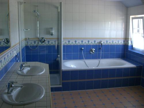 a blue tiled bathroom with two sinks and a tub at The Cosy Home in Hodenhagen
