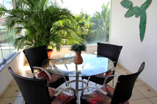 a glass table and chairs in a balcony with palm trees at Pousada Tia Nena in Olímpia