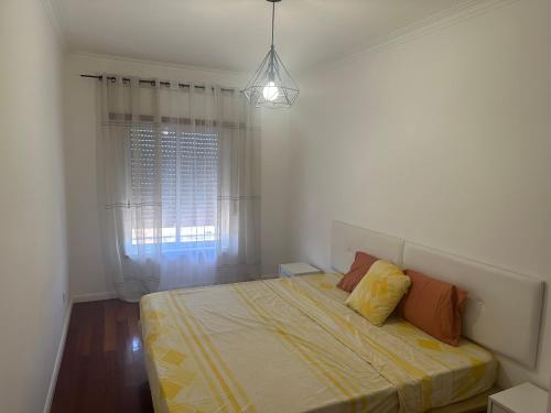 a bedroom with a bed with a yellow blanket and a window at Renna in Corroios