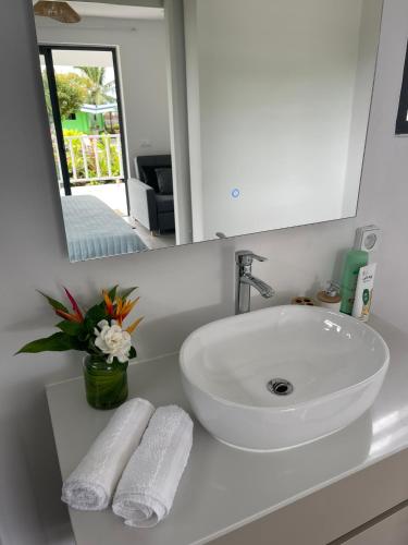 a bathroom with a sink and a mirror and towels at Teahupoo MANA VILLA in Toanoano