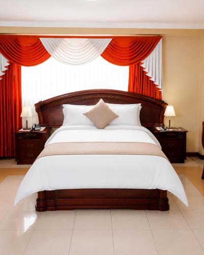 a bedroom with a large bed with red curtains at Hotel Raices in Ambato