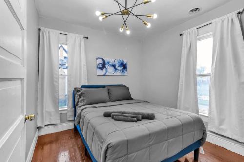 a bedroom with a bed with a chandelier and windows at 4BR Apt Pool Table Sleeps 9 Buffalo in Buffalo