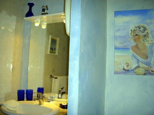 een badkamer met een wastafel en een schilderij van een vrouw bij La Becassiere in Thorenc