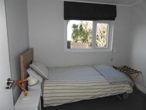 a bedroom with a bed and a window at Stirling St Surf Villa in Dunedin