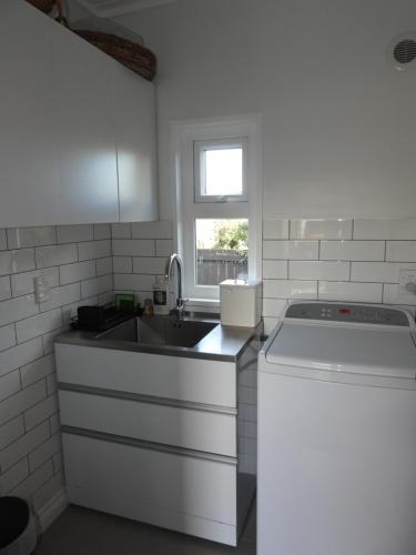 a white kitchen with a sink and a stove at Stirling St Surf Villa in Dunedin