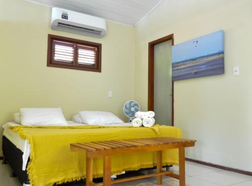 a bedroom with a bed with a yellow blanket and a bench at A Casa Azul in Barra Grande