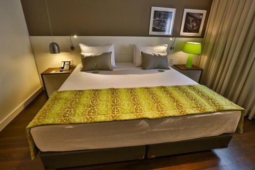a bedroom with a large bed with a yellow bedspread at Quality Hotel Flamboyant in Goiânia