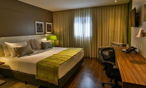 a hotel room with a bed and a desk and a desk at Quality Hotel Flamboyant in Goiânia