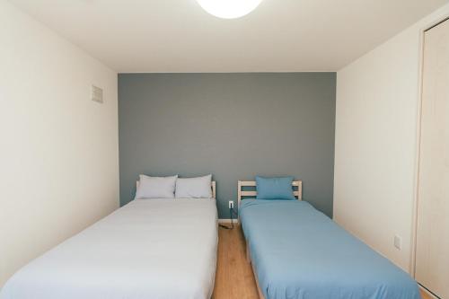 two beds in a small room with white walls at ビアンカ Bianca A号室 in Asahikawa