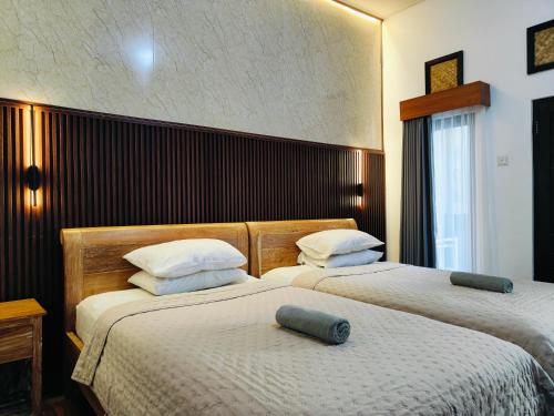a bedroom with two beds with white sheets at Ashana Hotel in Uluwatu
