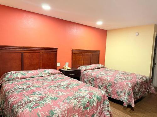 two beds in a hotel room with red walls at Budget Inn in Vidalia