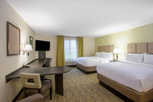 a hotel room with two beds and a desk at Candlewood Suites Bellevue by IHG in Bellevue