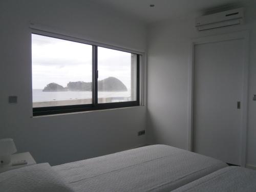 a bedroom with a bed and a large window at Casa Das Dias in Vila Franca do Campo