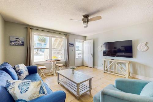 a living room with a blue couch and a tv at Spacious Condo with full kitchen shared pool and beach access in Perdido Key