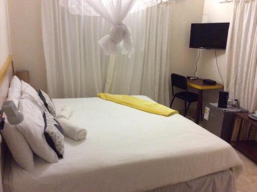 カサネにあるChiloto Guest Houseのベッドルーム1室(花が咲く窓、白いベッド1台付)