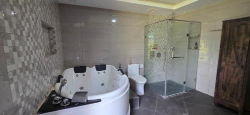 a bathroom with a tub and a toilet and a shower at RMB's Downton Place in Tagaytay