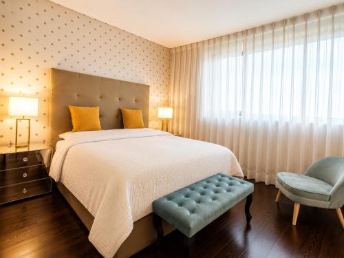 a bedroom with a large bed and a blue chair at Bom dia Parque Nações LisboaX in Lisbon