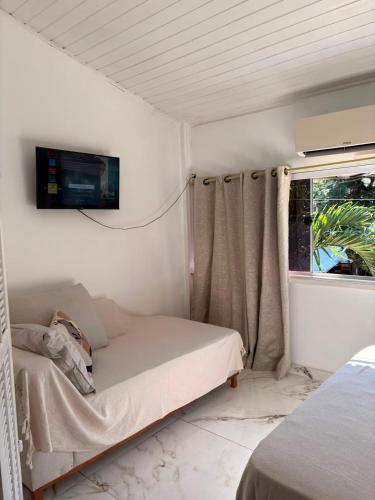 a bedroom with a bed and a tv on the wall at Caminho das Pedras Búzios in Búzios