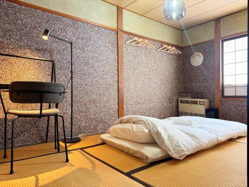 a bedroom with a bed and a chair in it at Hakuba Hospitality Inn YUKINOSO in Hakuba