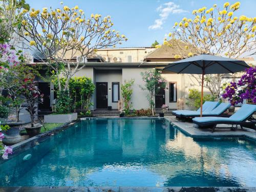 a swimming pool with two chairs and an umbrella at Ashana Hotel in Uluwatu
