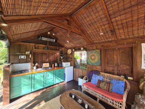 an open kitchen and living room with wooden walls at The Bali Room in Coromandel Town