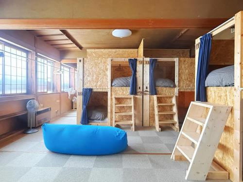 a room with two bunk beds and a blue couch at Hakuba Hospitality Inn YUKINOSO in Hakuba