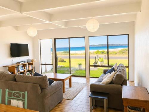 a living room with two couches and a television at Ocean Front on Malibu in Bawley Point