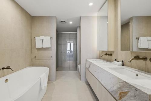 a white bathroom with two sinks and a shower at Amaya in Gold Coast